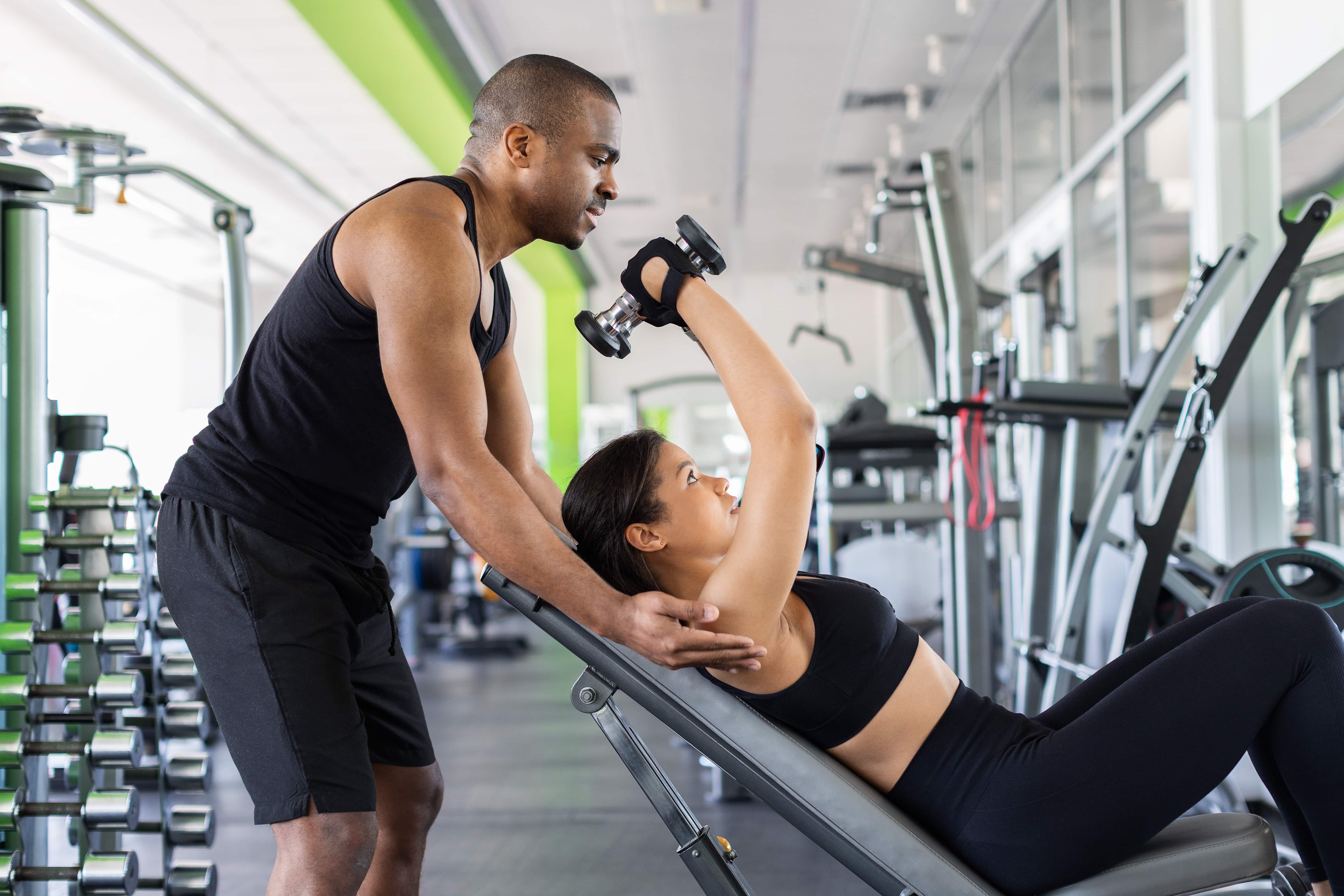 personal trainer assisting someone lifting weights