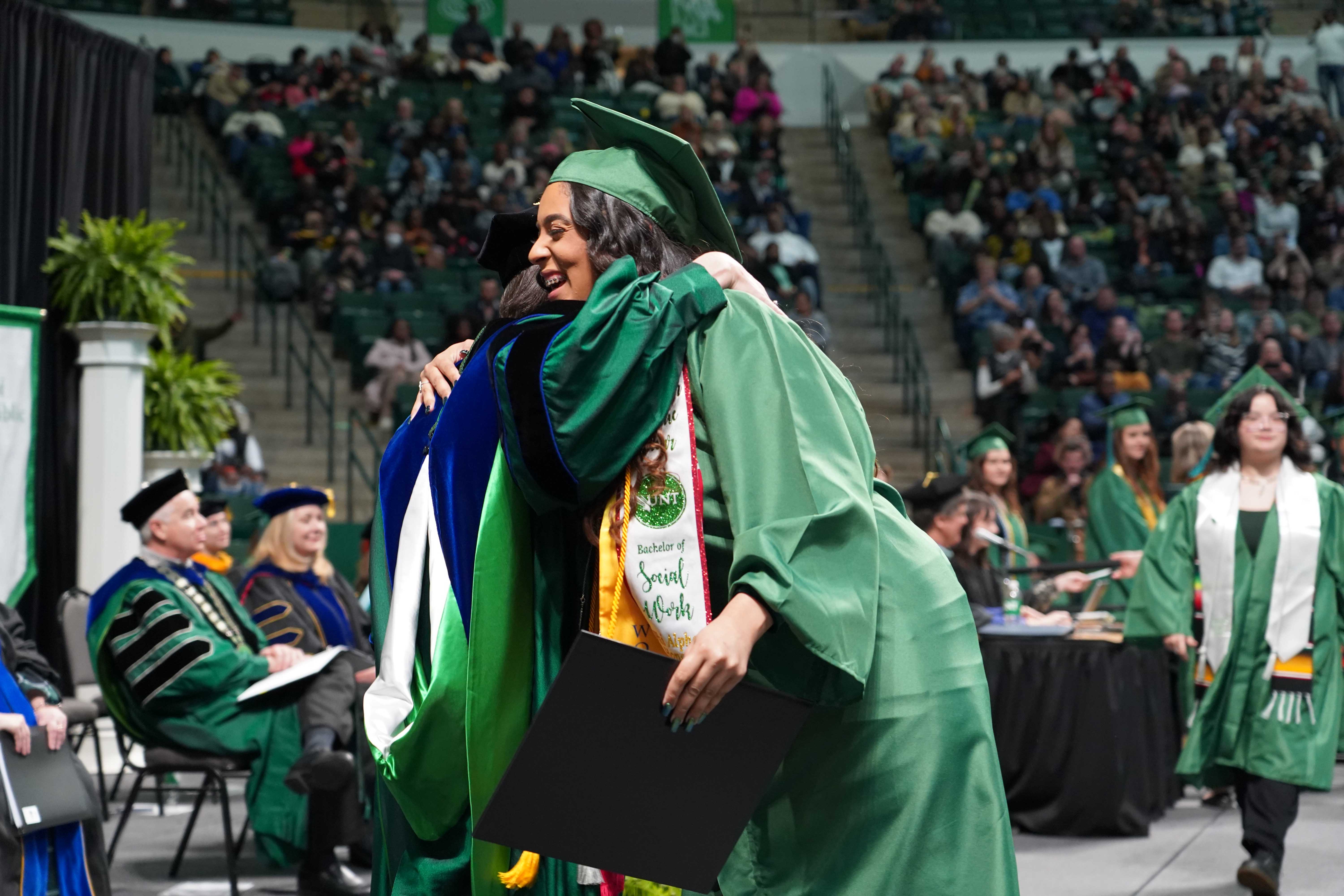 Social Work graduate hugging department chair at commencement
